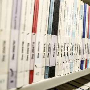 Dissertationen in der Bibliothek Bücher mit der Aufschrift Dissertation auf dem Buchrücken im Bücherregal der Bibliothek
